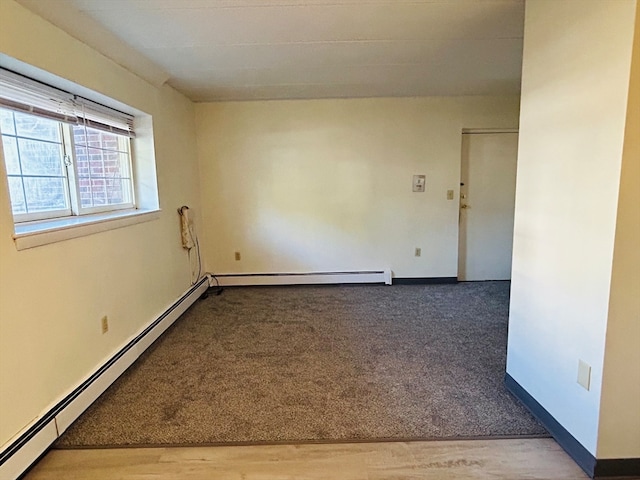 empty room featuring a baseboard heating unit and hardwood / wood-style flooring