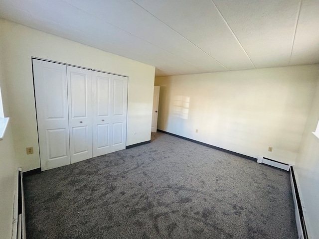 unfurnished bedroom with a closet, baseboard heating, and dark colored carpet