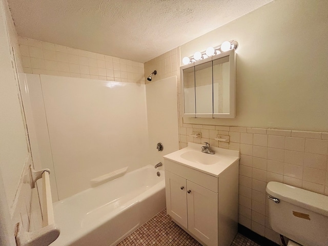 full bathroom with toilet, tiled shower / bath combo, vanity, and tile walls