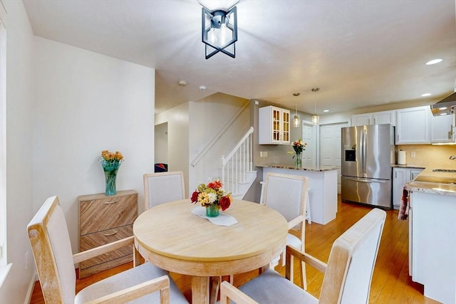 dining room featuring light wood-type flooring, stairway, and recessed lighting