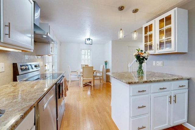 kitchen with light wood-style flooring, decorative backsplash, glass insert cabinets, stainless steel range with electric cooktop, and white cabinetry