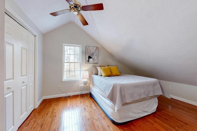 unfurnished bedroom with light wood-style floors, vaulted ceiling, baseboards, and ceiling fan