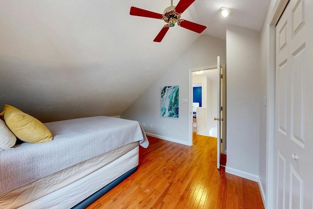 bedroom with light wood-type flooring, ceiling fan, lofted ceiling, and baseboards