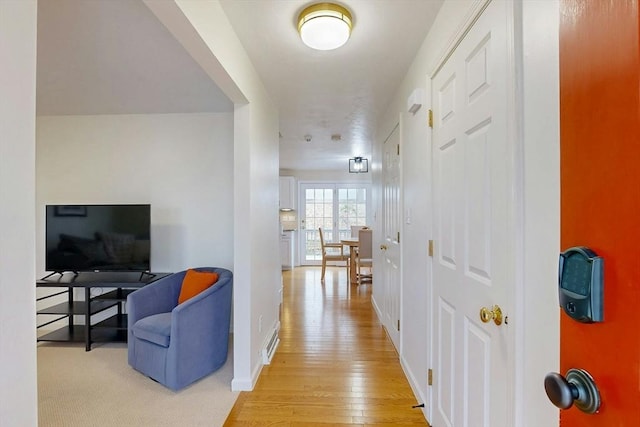 hall with baseboards and light wood finished floors