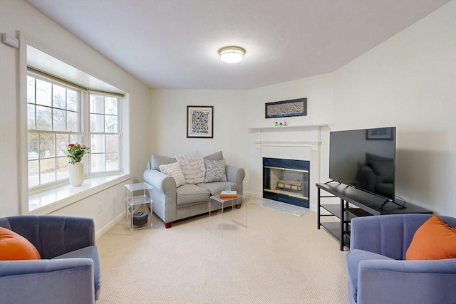 living area with carpet, baseboards, and a glass covered fireplace