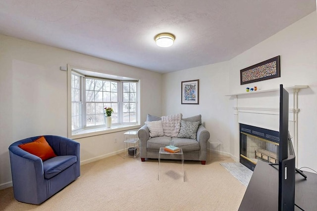 carpeted living area featuring a fireplace with flush hearth and baseboards