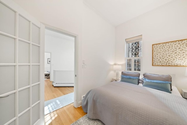 bedroom with light wood finished floors, a baseboard heating unit, and lofted ceiling