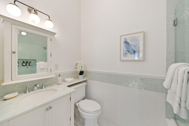 full bath with tile walls, a wainscoted wall, toilet, and vanity