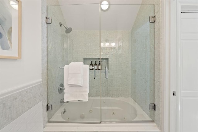 bathroom featuring tile walls and a combined bath / shower with jetted tub