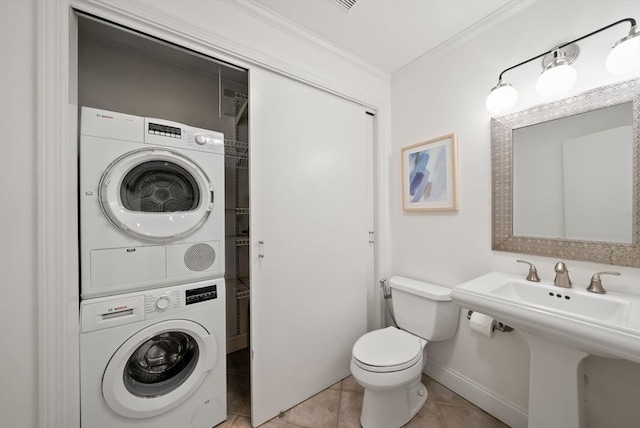 bathroom with toilet, stacked washer and clothes dryer, ornamental molding, tile patterned flooring, and baseboards