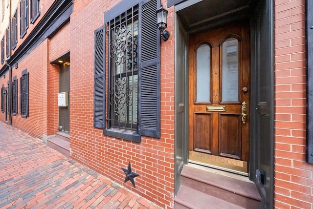 view of exterior entry featuring brick siding