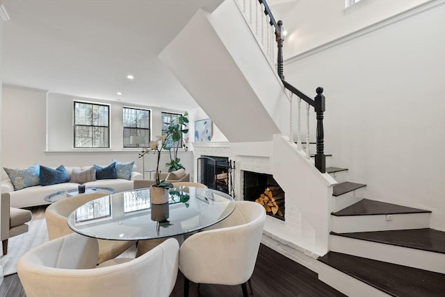 dining area featuring recessed lighting, a fireplace, stairs, and wood finished floors