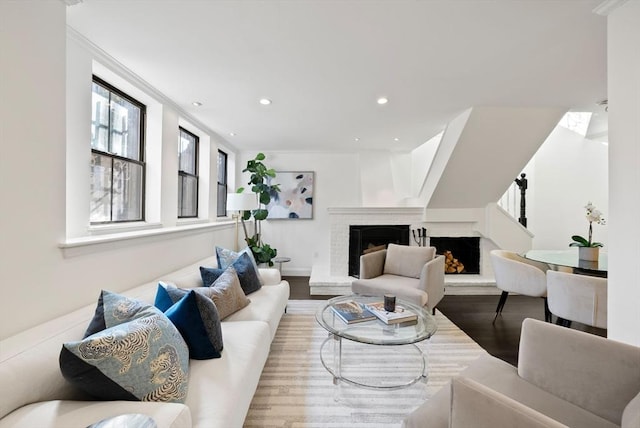 living area with wood finished floors, crown molding, recessed lighting, and a fireplace with raised hearth