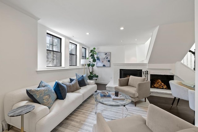 living area with recessed lighting, wood finished floors, a fireplace, and ornamental molding