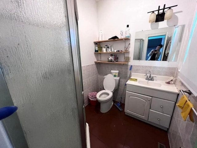 bathroom with vanity, toilet, an enclosed shower, and tile walls