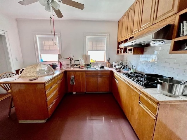 kitchen with backsplash, sink, gas stovetop, a kitchen bar, and kitchen peninsula