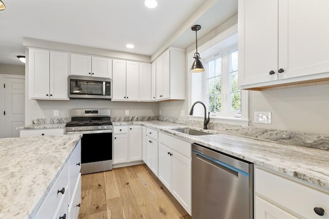 kitchen featuring decorative light fixtures, stainless steel appliances, white cabinetry, and sink