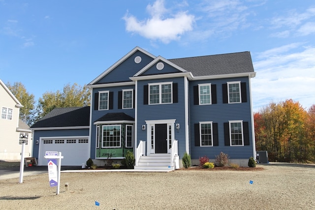 colonial house featuring central air condition unit and a garage