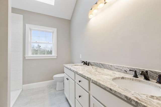 bathroom with vanity, toilet, and lofted ceiling with skylight