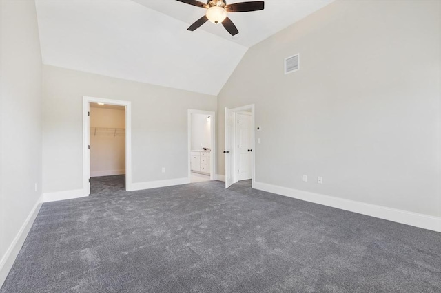 unfurnished bedroom featuring a walk in closet, vaulted ceiling, ceiling fan, dark colored carpet, and a closet