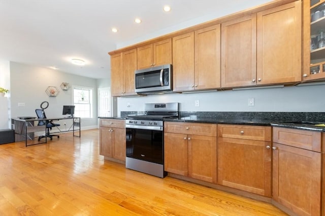 kitchen featuring light wood-style flooring, stainless steel appliances, glass insert cabinets, and brown cabinets