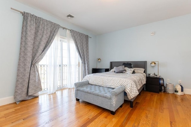 bedroom with baseboards, wood finished floors, and access to exterior