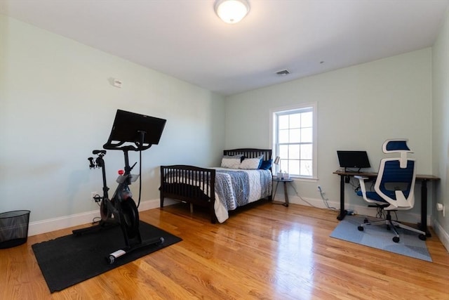 bedroom with visible vents, baseboards, and wood finished floors