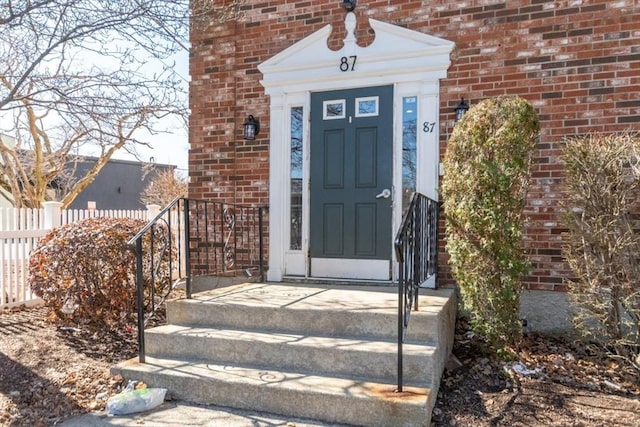 property entrance with fence and brick siding