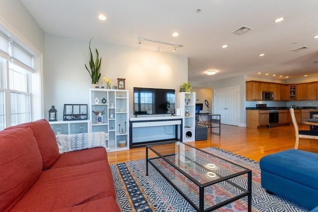 living area with light wood-style flooring, rail lighting, recessed lighting, and visible vents