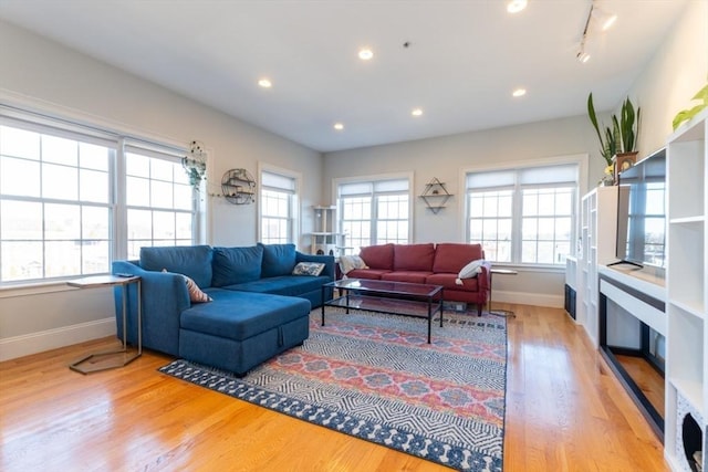 living area featuring plenty of natural light, light wood-type flooring, and baseboards