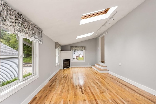 46 Blackmer, Sudbury, MA 01776 - unfurnished living room featuring a skylight, light wood-type flooring, a fireplace, track lighting, and baseboards