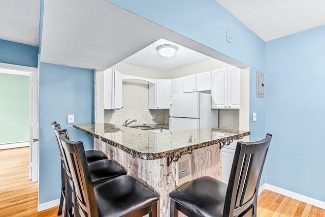 kitchen featuring dark stone counters, a kitchen breakfast bar, backsplash, and freestanding refrigerator