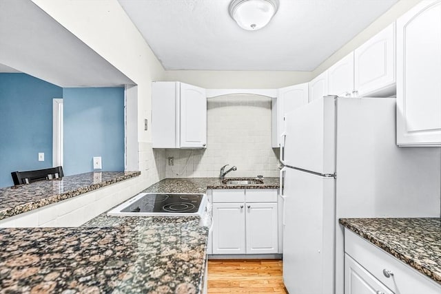 kitchen with dark stone counters, white cabinets, and a sink