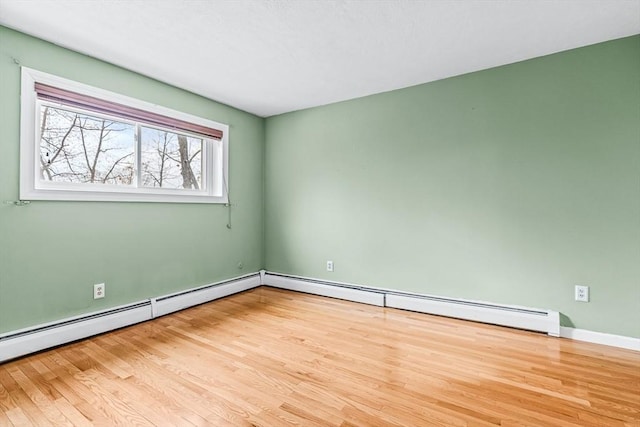 spare room featuring a baseboard heating unit and wood finished floors