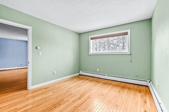 spare room featuring a textured ceiling, a baseboard heating unit, wood-type flooring, and a baseboard radiator