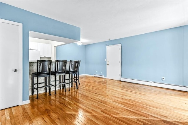 kitchen with refrigerator, white cabinetry, light wood-style floors, baseboards, and baseboard heating