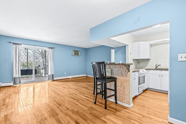 kitchen with a breakfast bar, white electric range, white cabinetry, a peninsula, and baseboard heating