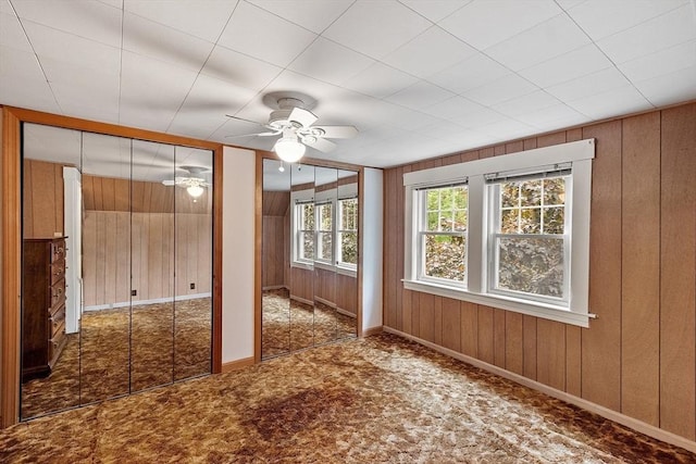 74 W Main St, Westminster, MA 01473 - unfurnished bedroom featuring wooden walls, ceiling fan, two closets, and carpet