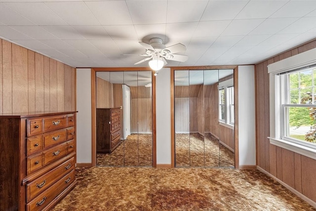 74 W Main St, Westminster, MA 01473 - unfurnished bedroom featuring two closets, wood walls, multiple windows, and a ceiling fan