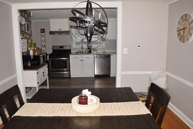 dining space with dark hardwood / wood-style flooring, ornamental molding, sink, and a chandelier