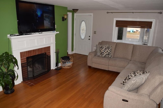 living room with hardwood / wood-style floors and a brick fireplace