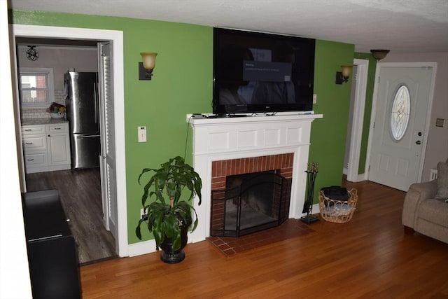 living room featuring hardwood / wood-style flooring and a brick fireplace