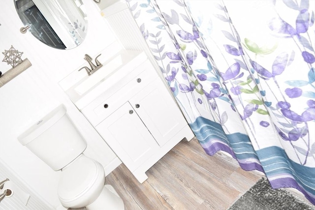 bathroom with wood-type flooring, vanity, toilet, and curtained shower