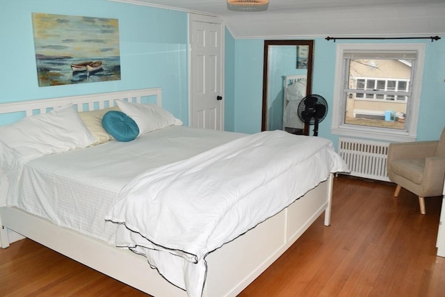 bedroom with hardwood / wood-style flooring and radiator heating unit