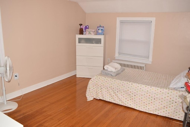 bedroom with radiator, vaulted ceiling, and hardwood / wood-style flooring