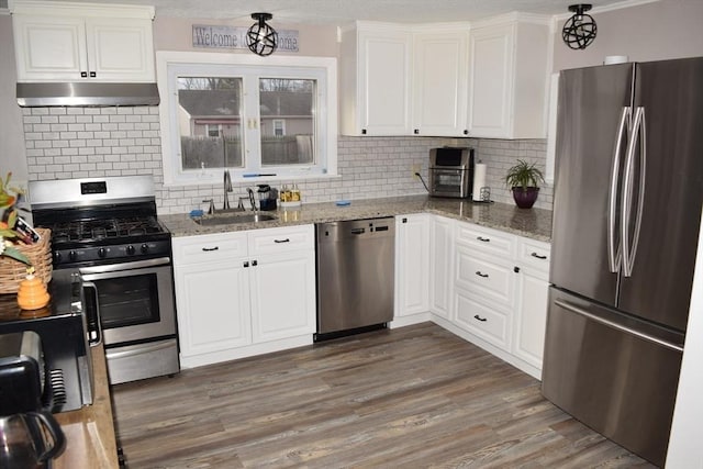 kitchen with sink, light stone countertops, appliances with stainless steel finishes, tasteful backsplash, and white cabinetry