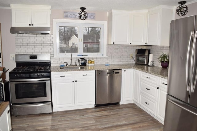 kitchen with white cabinets, stone countertops, stainless steel appliances, and tasteful backsplash