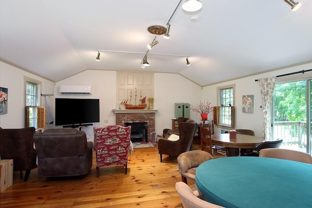 living room with hardwood / wood-style floors, lofted ceiling, an AC wall unit, and a brick fireplace