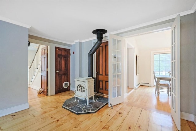 interior space featuring a wood stove, ornamental molding, stairs, wood-type flooring, and baseboards