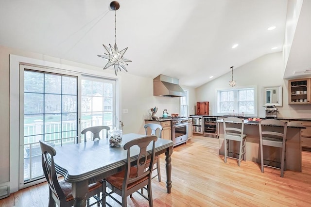 dining space with a notable chandelier, light wood-type flooring, recessed lighting, beverage cooler, and lofted ceiling